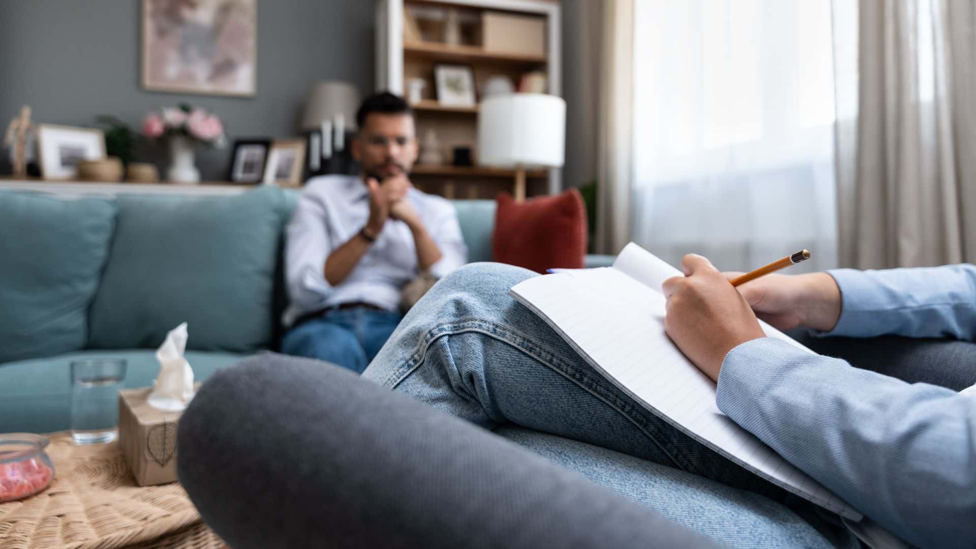 A client speaking with a counselor in a quiet therapy room.