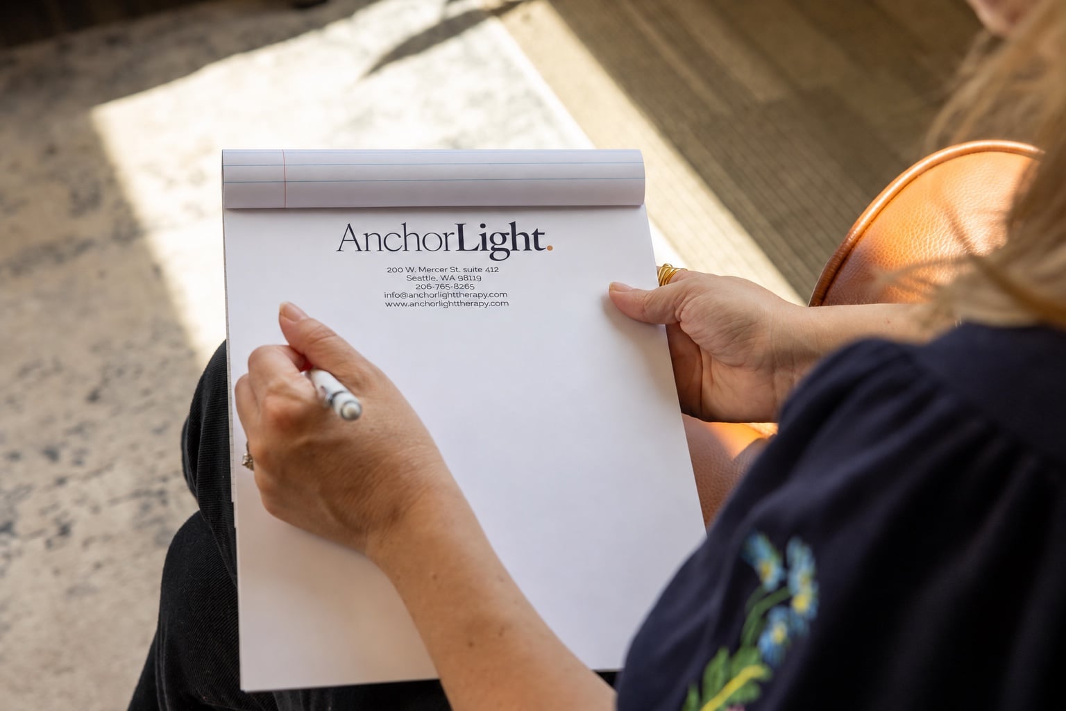 AnchorLight-branded notepad held by a therapist